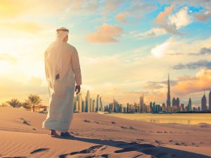 Φωτογραφία που απεικονίζει ντόπιο Άραβα να ατενίζει την πόλη του Ντουμπάι μέσα από την έρημο. Η έρημος και οι ουρανοξύστες είναι ένα κοινό θέαμα που αντικρύζει κάθε ταξιδιώτης στην εκδρομή στο Ντουμπάι που διοργανώνει το ταξιδιωτικό γραφείο diontours & red elephant